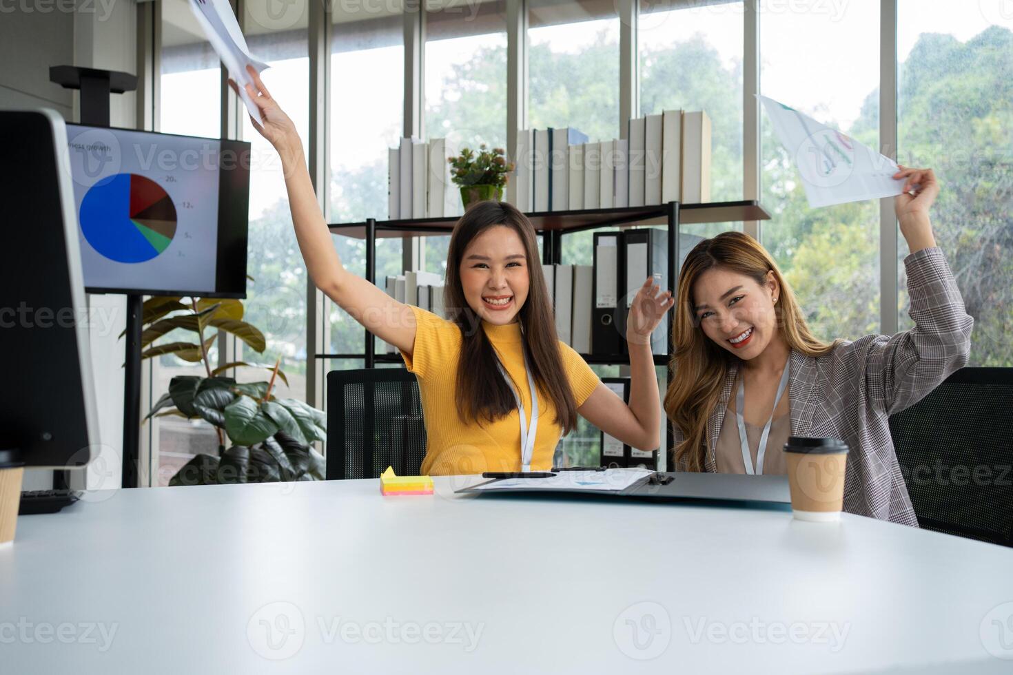 Asian smart Office or businesswoman excited successful business people, celebrating win. Two businesswoman looking at a monthly summary of sales that exceed sales targets and achieve profitable growth photo