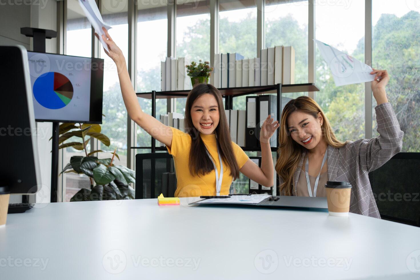 asiático inteligente oficina o mujer de negocios emocionado exitoso negocio gente, celebrando ganar. dos mujer de negocios mirando a un mensual resumen de ventas ese exceder ventas objetivos y lograr rentable crecimiento foto