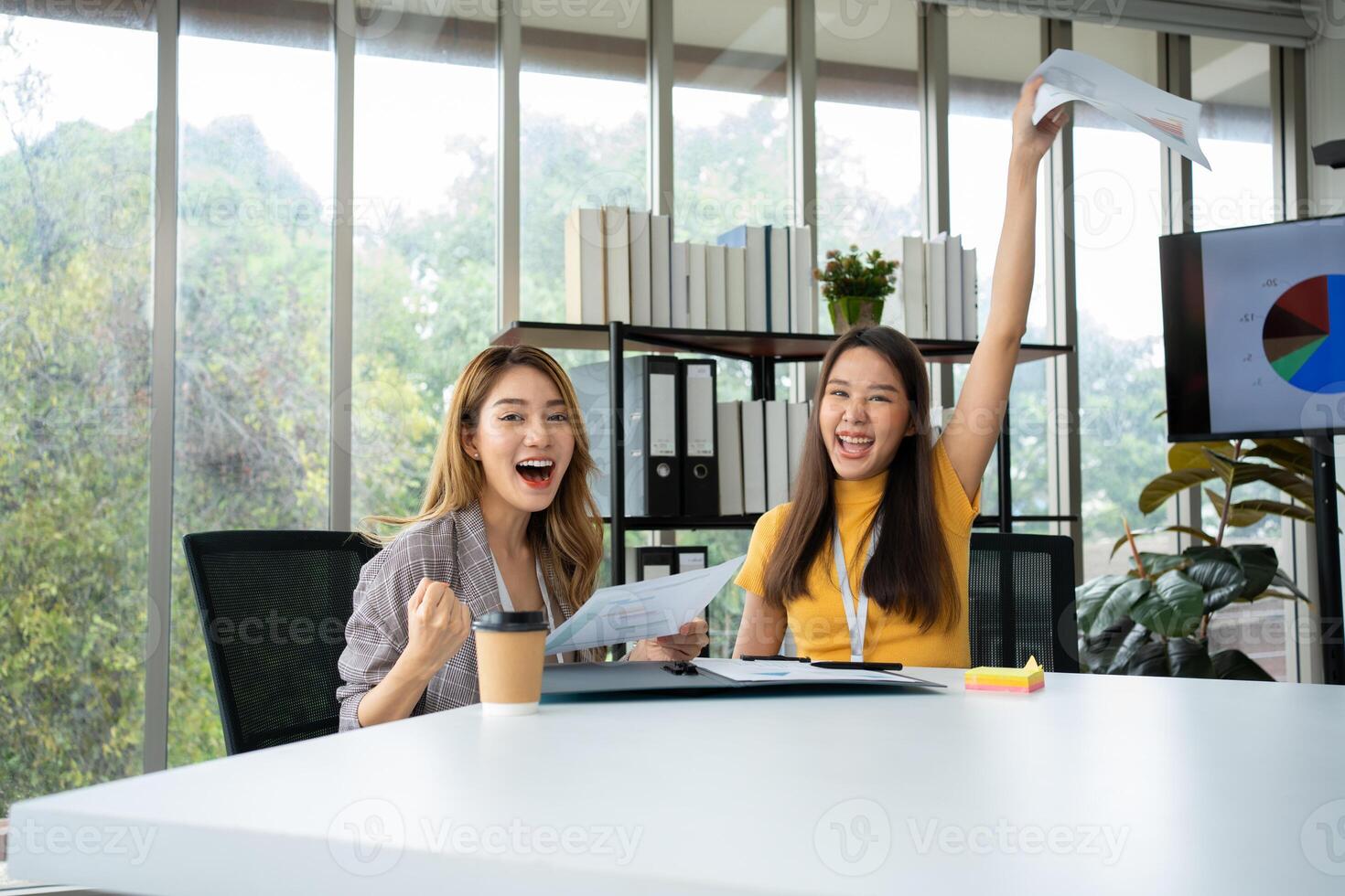 asiático inteligente oficina o mujer de negocios emocionado exitoso negocio gente, celebrando ganar. dos mujer de negocios mirando a un mensual resumen de ventas ese exceder ventas objetivos y lograr rentable crecimiento foto