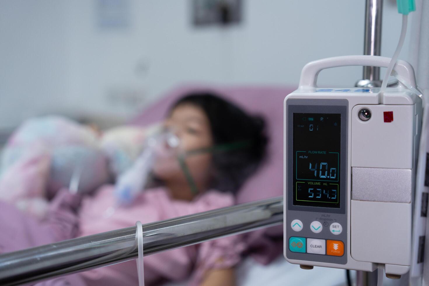 A little Asian girl has an oxygen mask and breathing through a nebulizer at the hospital. Concept of bronchitis, respiratory and Medical treatment, inhaling medicine, mist, from a nebulizer. photo