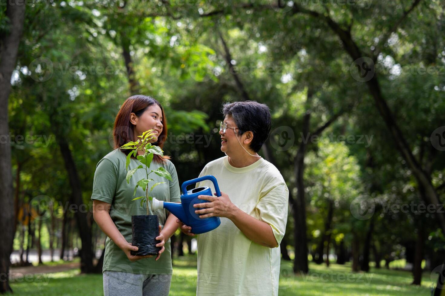 Portrait, Asian family mom and daughter plant sapling tree outdoors in nature park, Concept of happy retirement With care from a caregiver and Savings and senior health insurance, Happy family photo