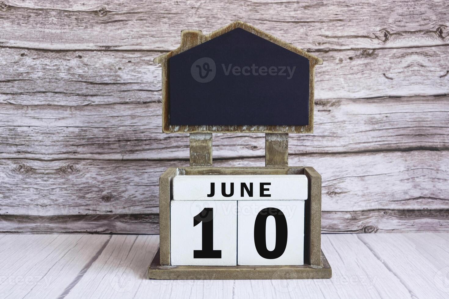 Chalkboard with June 10 date on white cube block on wooden table. photo