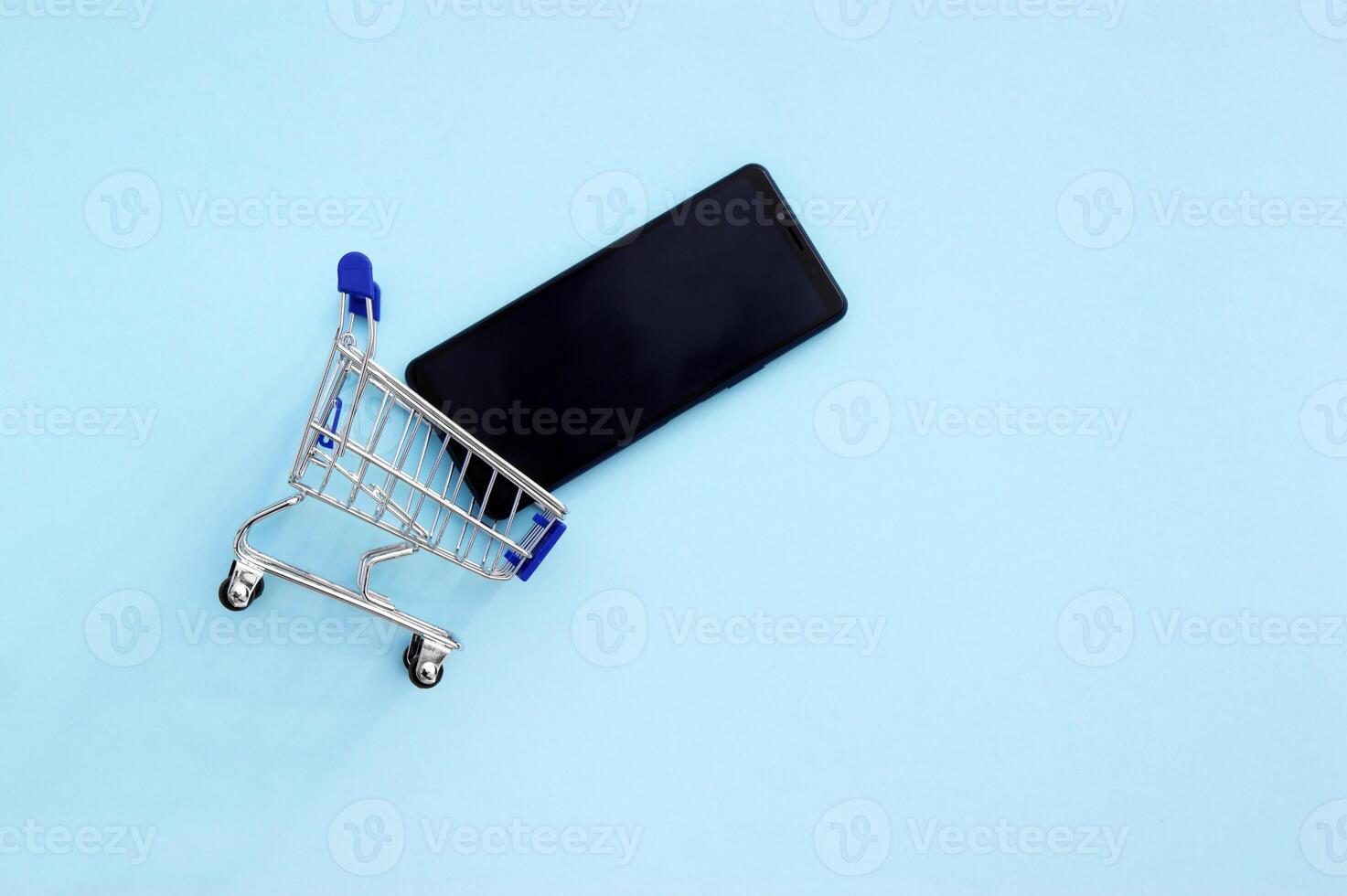 Basket for shopping with a smartphone on a blue background. photo