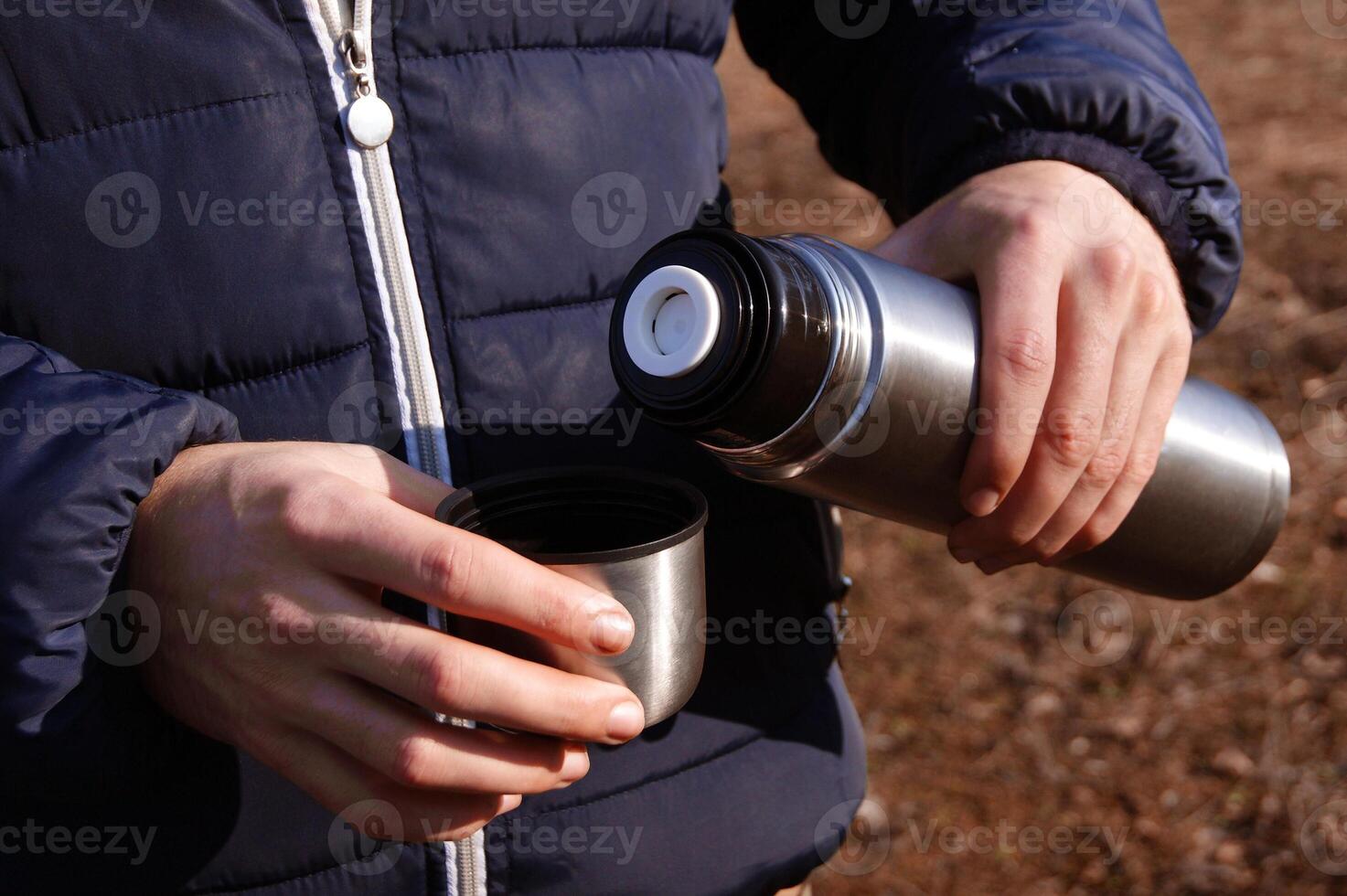 Man's hands pouring fresh hot cocoa from thermos to cup. photo
