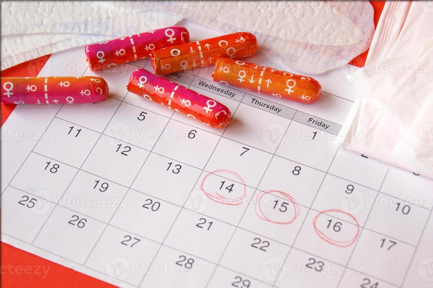 Menstrual pads and tampons on menstruation period calendar with on red background. photo