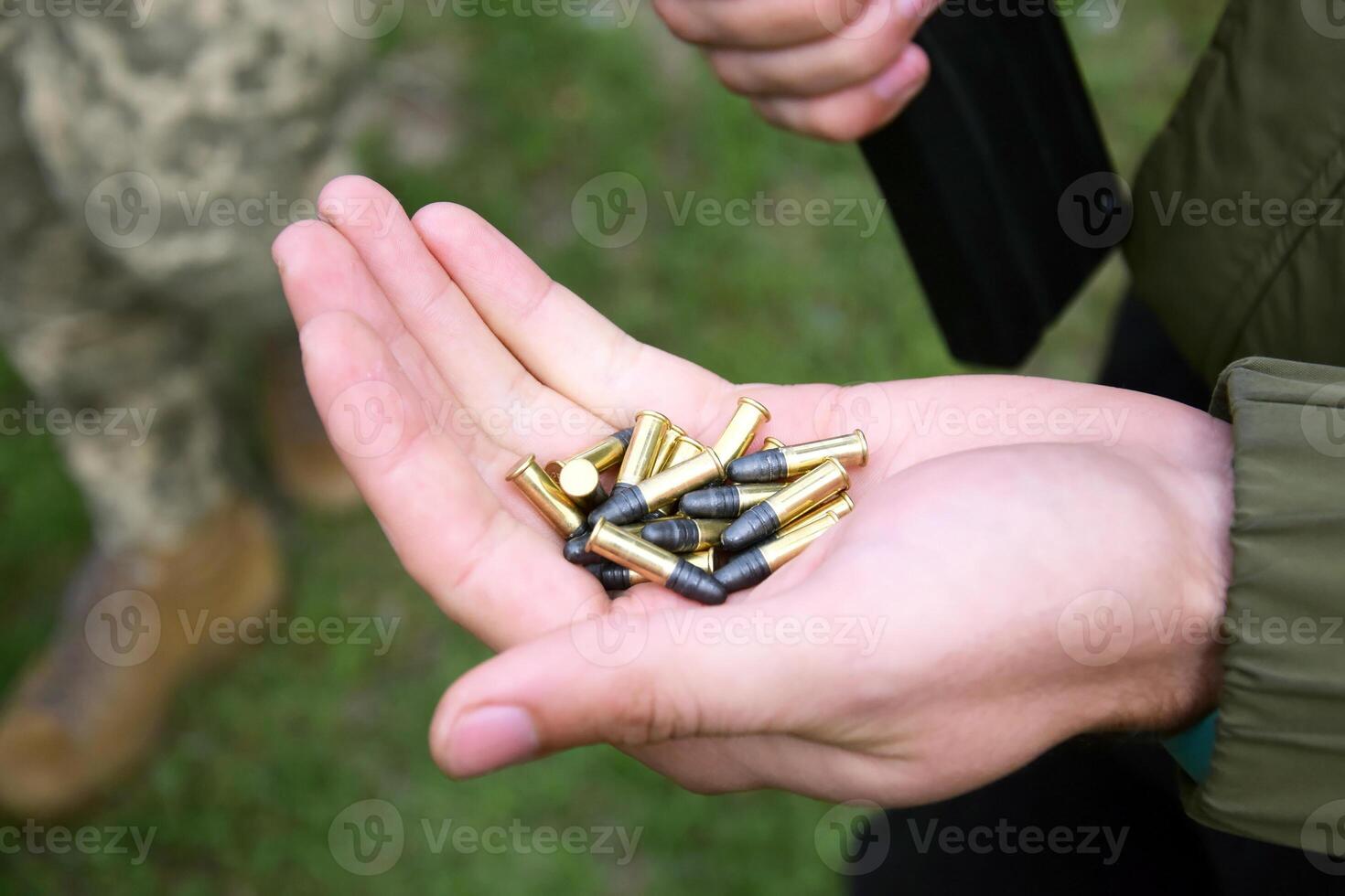 A pile of 22 LR bullets with a round head in the guy's hand. photo