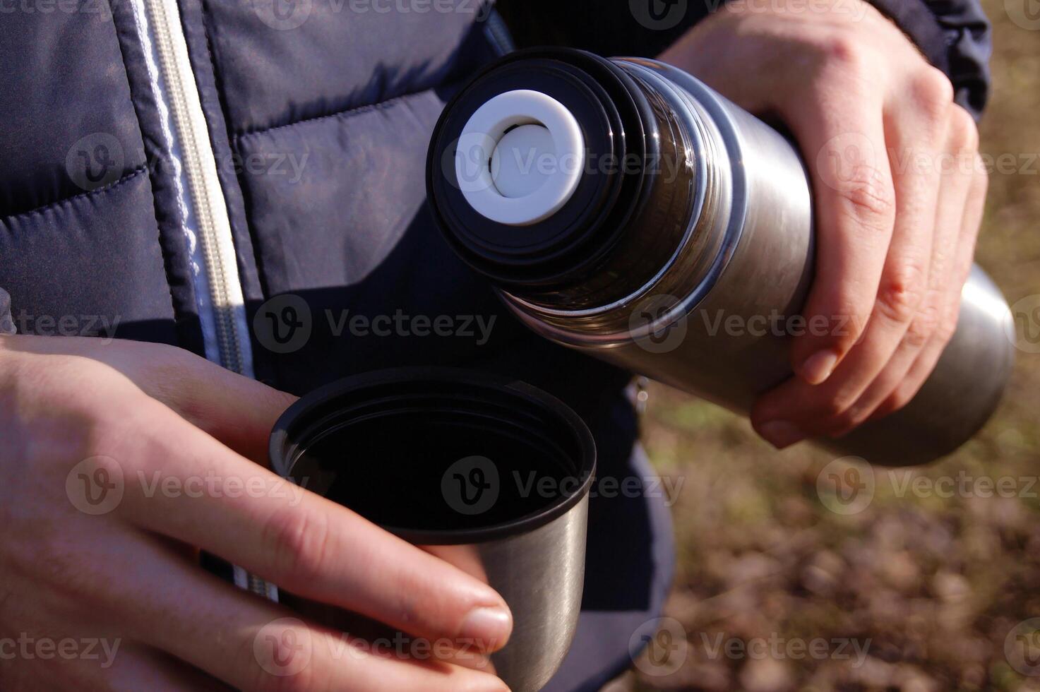 Man's hands pouring fresh hot cocoa from thermos to cup. photo