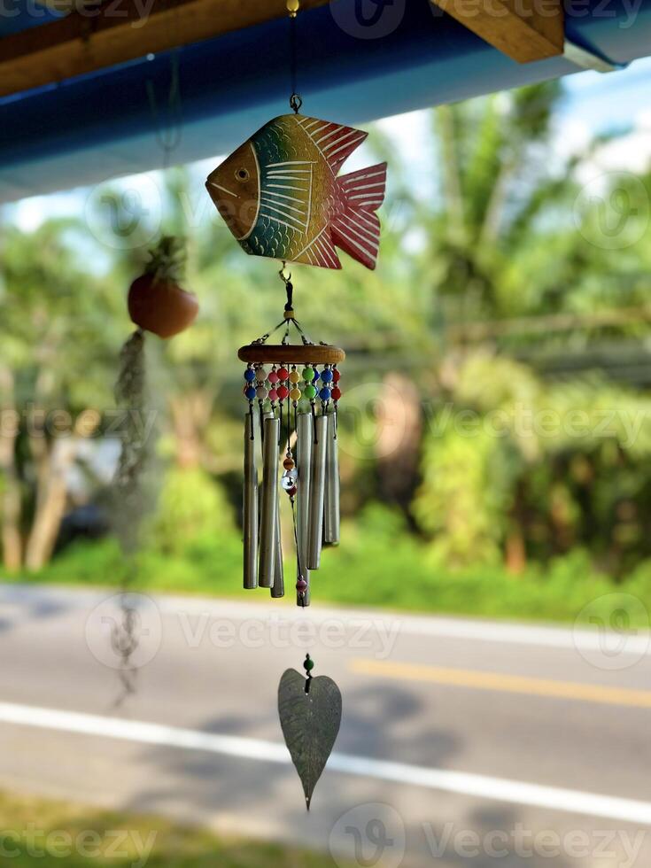 un pintado a mano pescado viento repicar con metal tubos y rosario colgando al aire libre, un caprichoso adición a jardín decoración foto