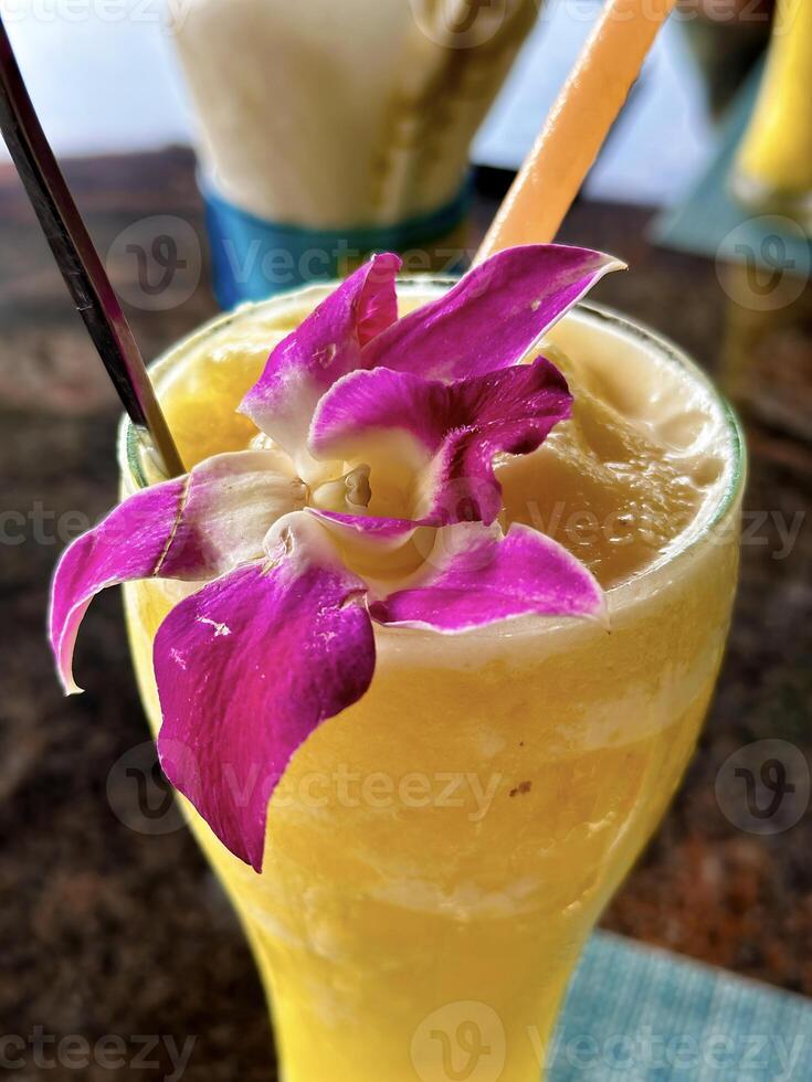 A vibrant tropical cocktail adorned with a pink orchid, showcasing freshness and exotic vacation vibes in a close-up shot photo