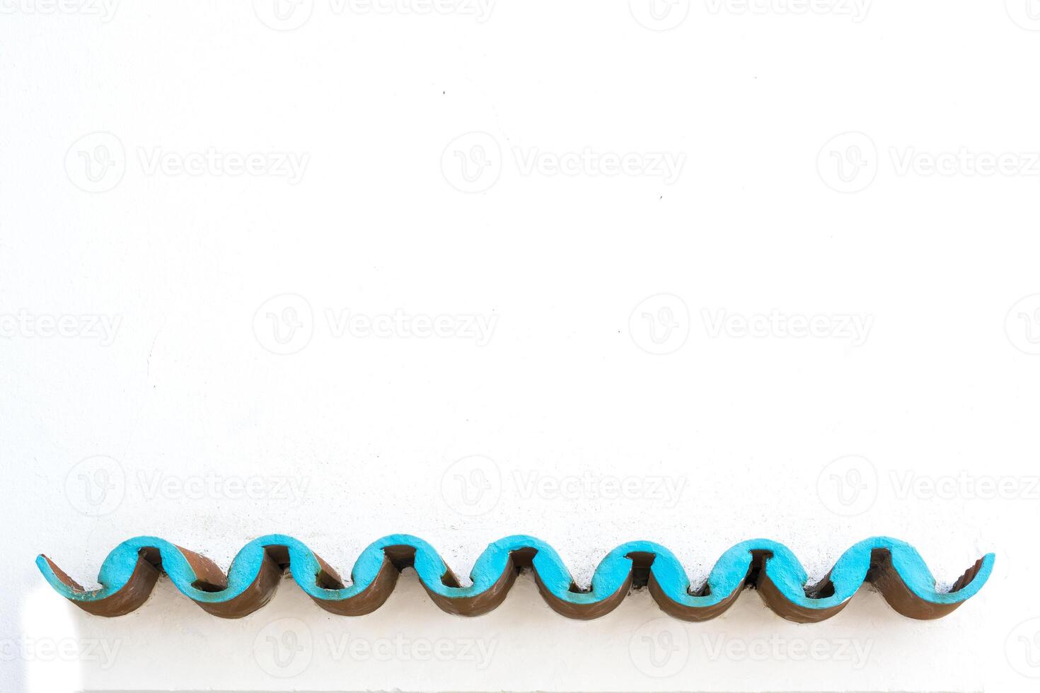 White concrete wall with blue turquoise waves formed by overlapping roof tiles. photo