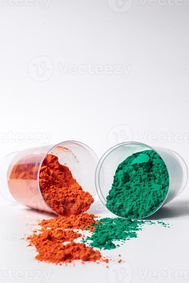 Colorful holi powder in a glass container leaning against a white background. photo
