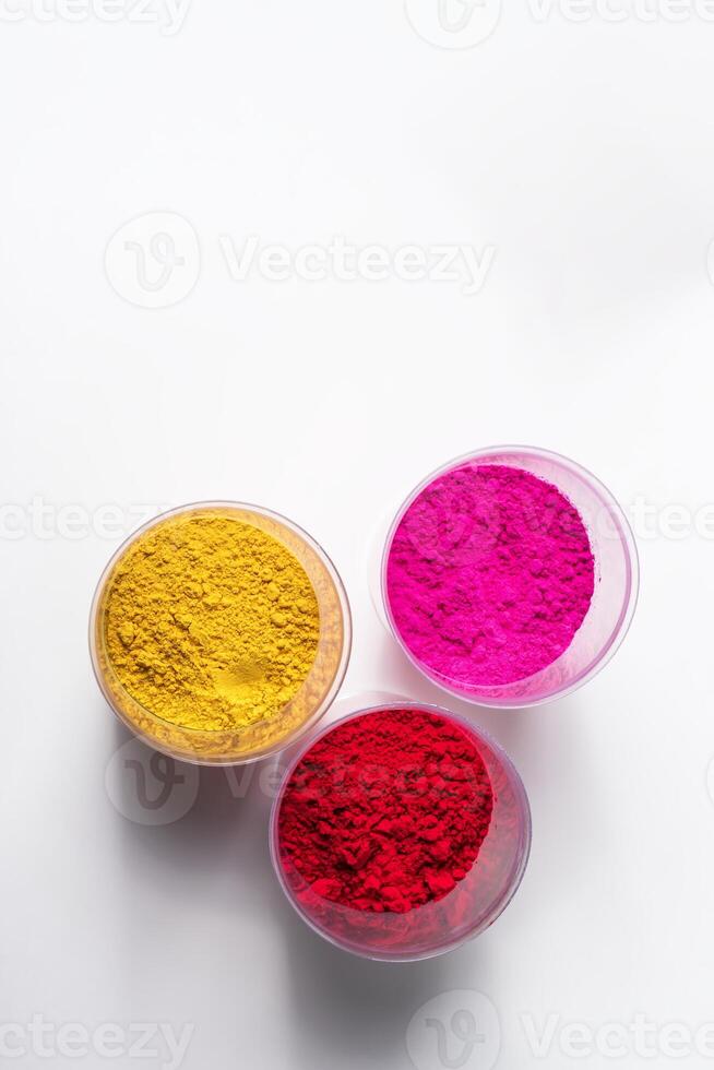 Colorful holi powder in plastic containers isolated on white background. photo