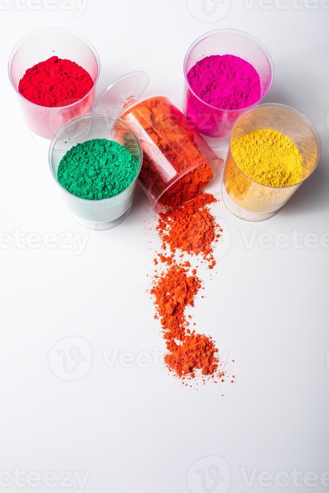 Vertical shot of colorful holi powder in plastic cups on white background with copy space. photo