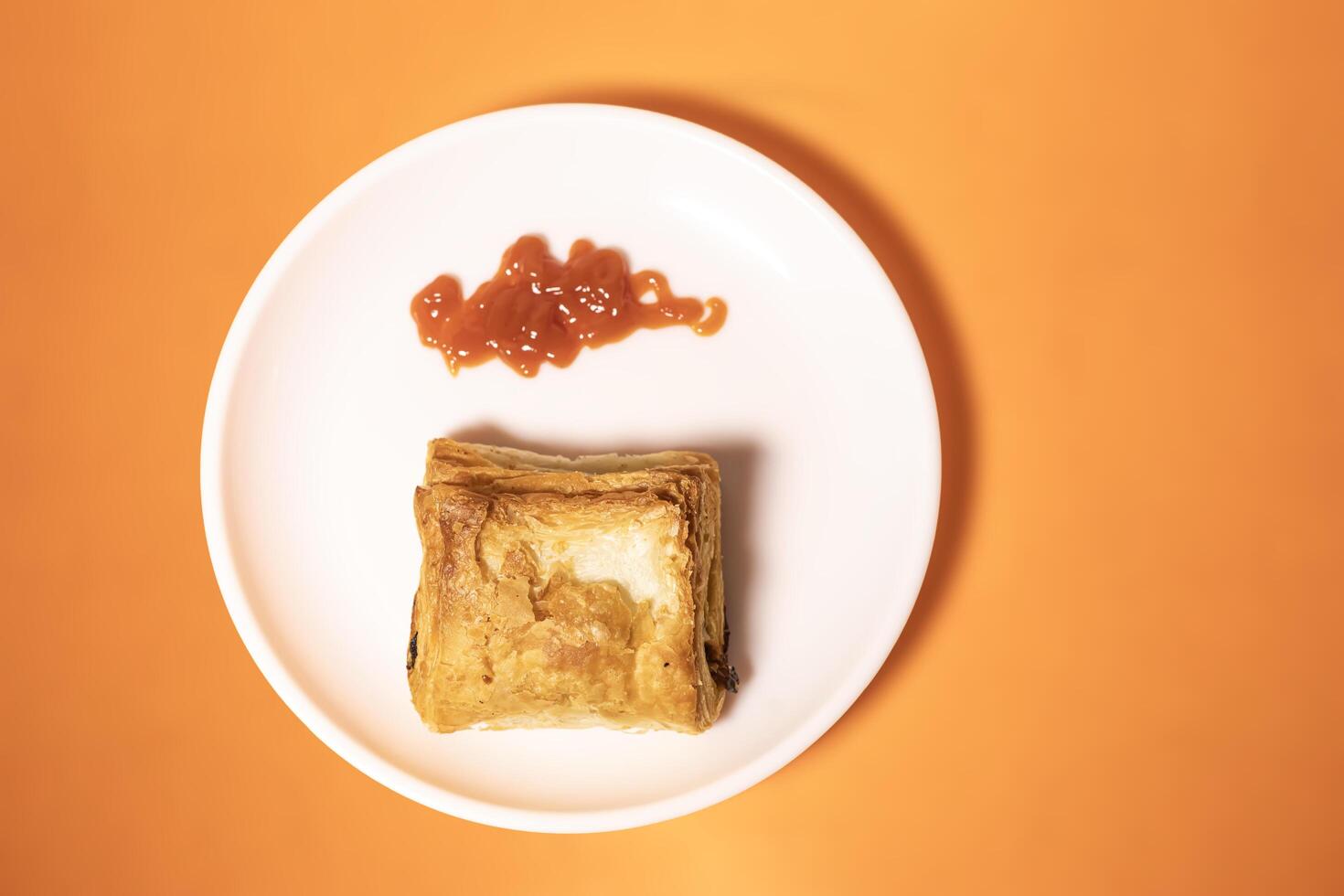 Vegetable puff with ketchup on white plate on orange background. photo