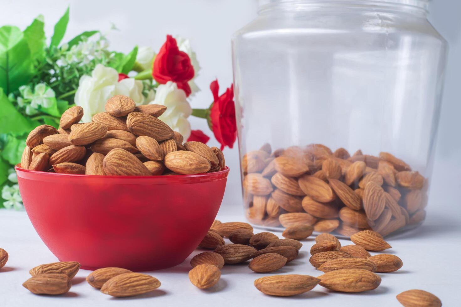 almendra en un rojo cuenco en un blanco antecedentes con flores sano alimento. foto