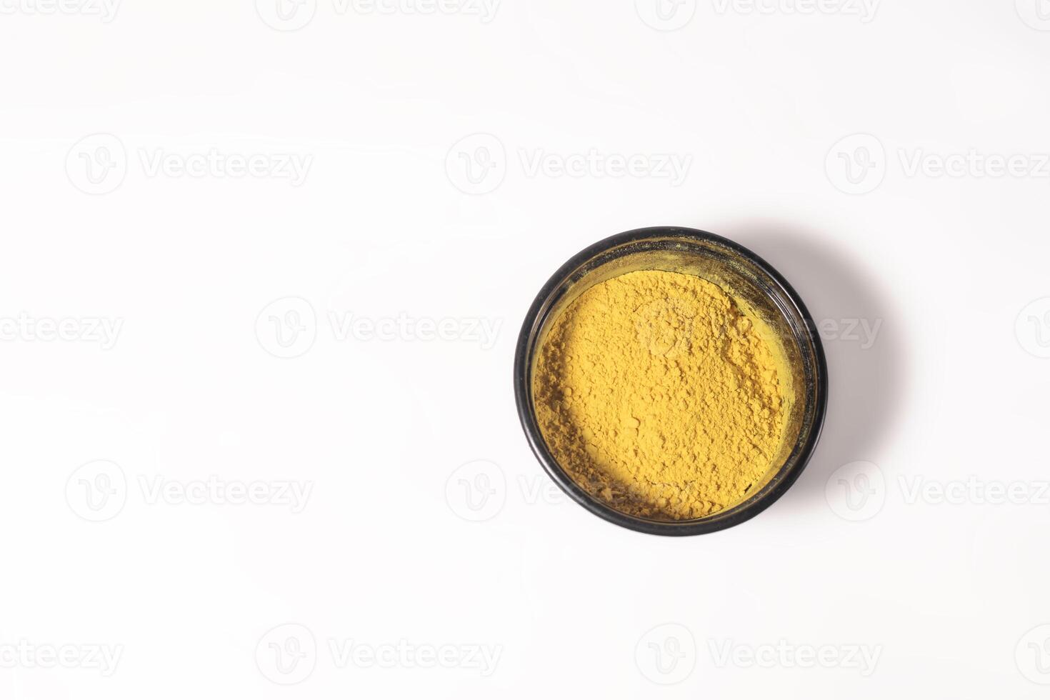 Top view of yellow holi powder in plastic box on white background for Indian festival Holi. Space for text. photo