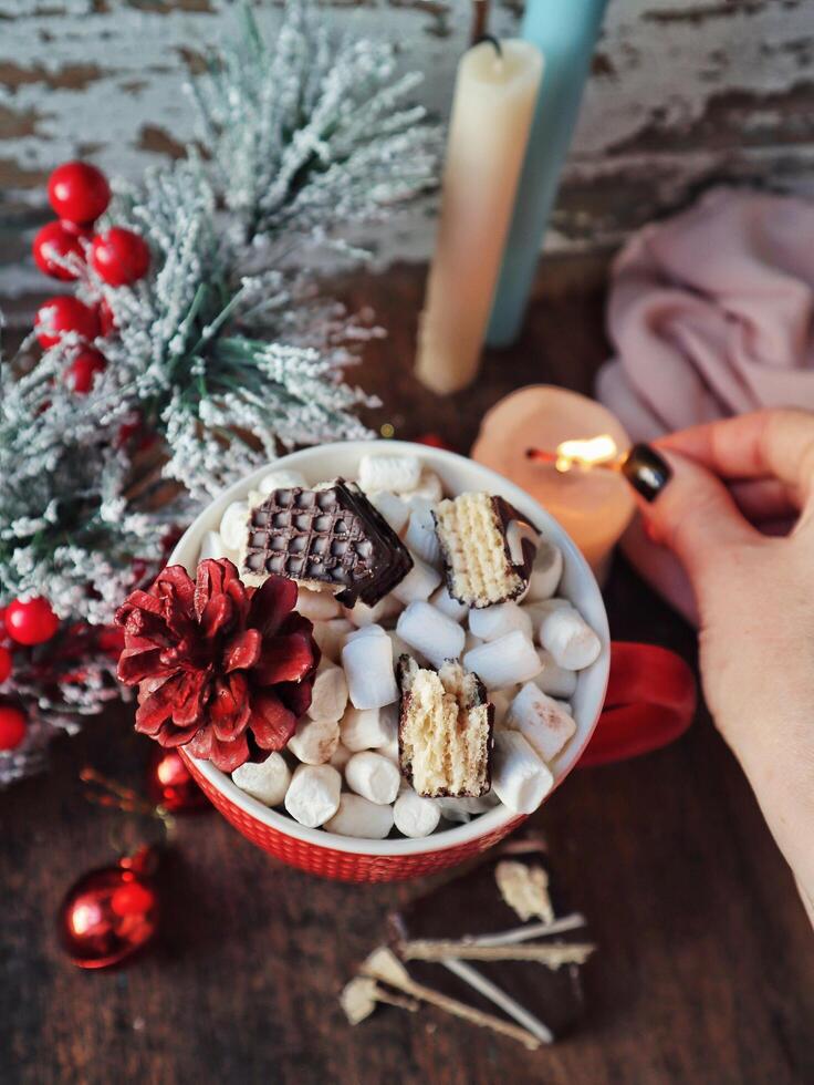 Cup of hot cocoa with marshmallows and cinnamon on a table with christmas decoration photo