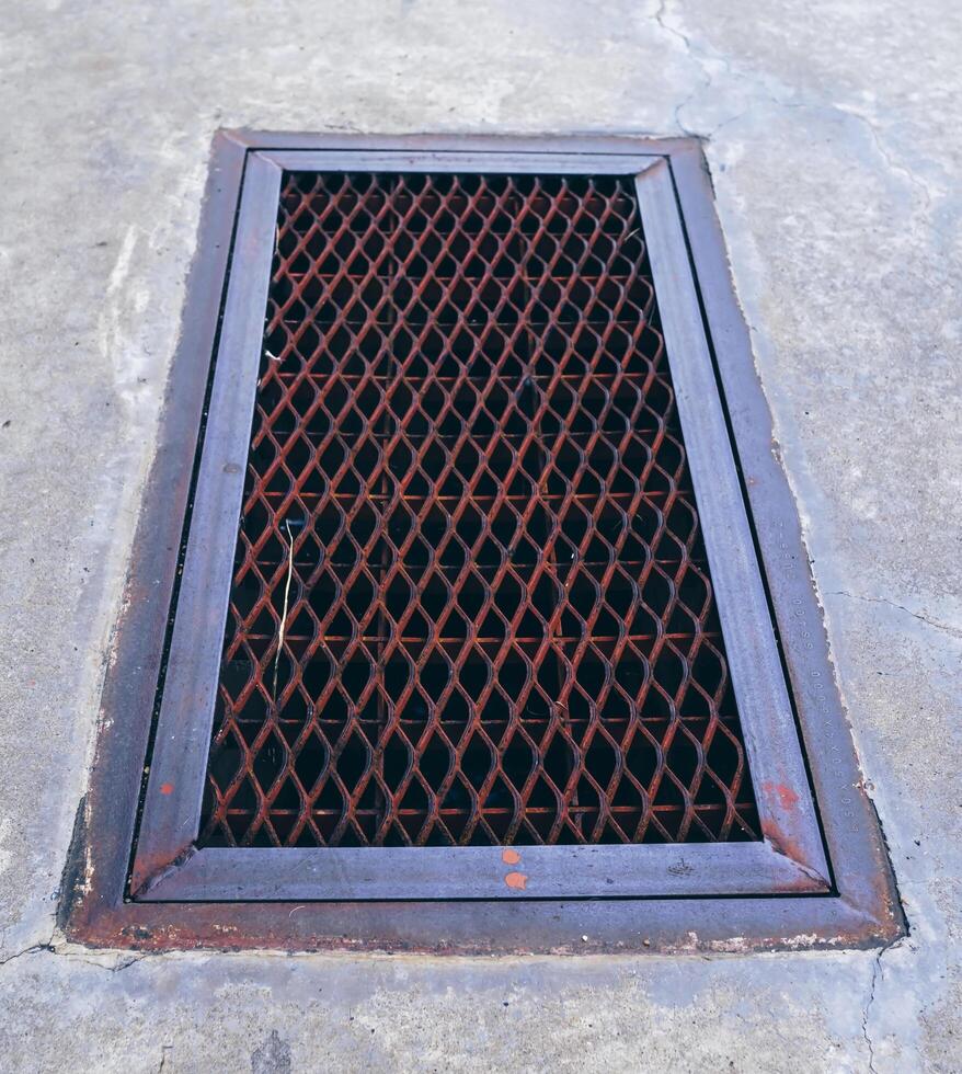 The steel drain grate cover is closed on the cement walkway. photo
