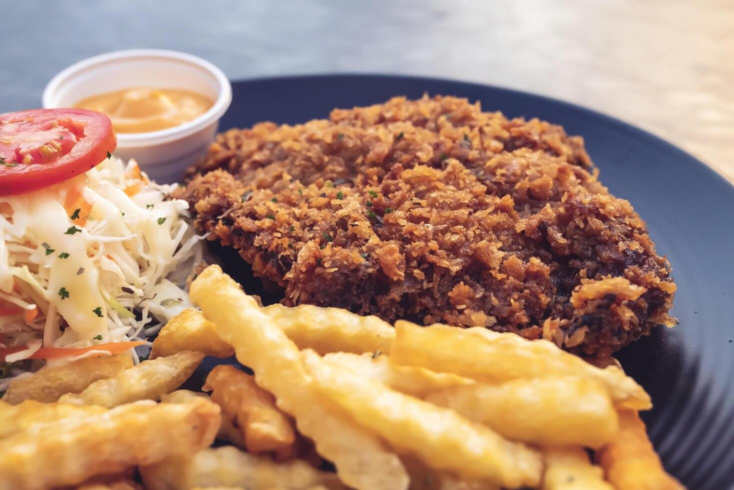 Pork batter with potato sticks and mayonnaise on a black plate photo