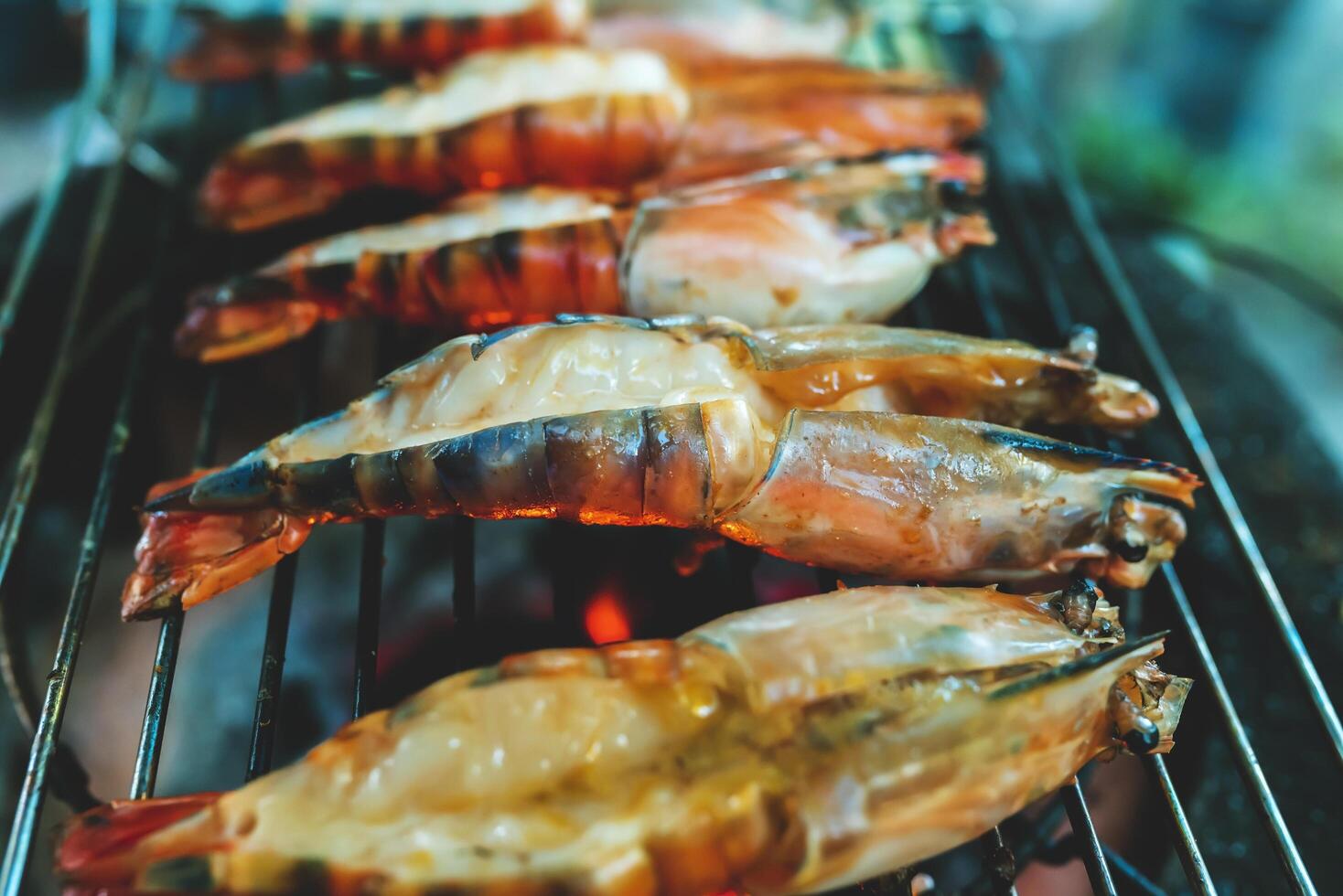 Large prawns are placed on an iron griddle and grilled over a hot coal stove. photo