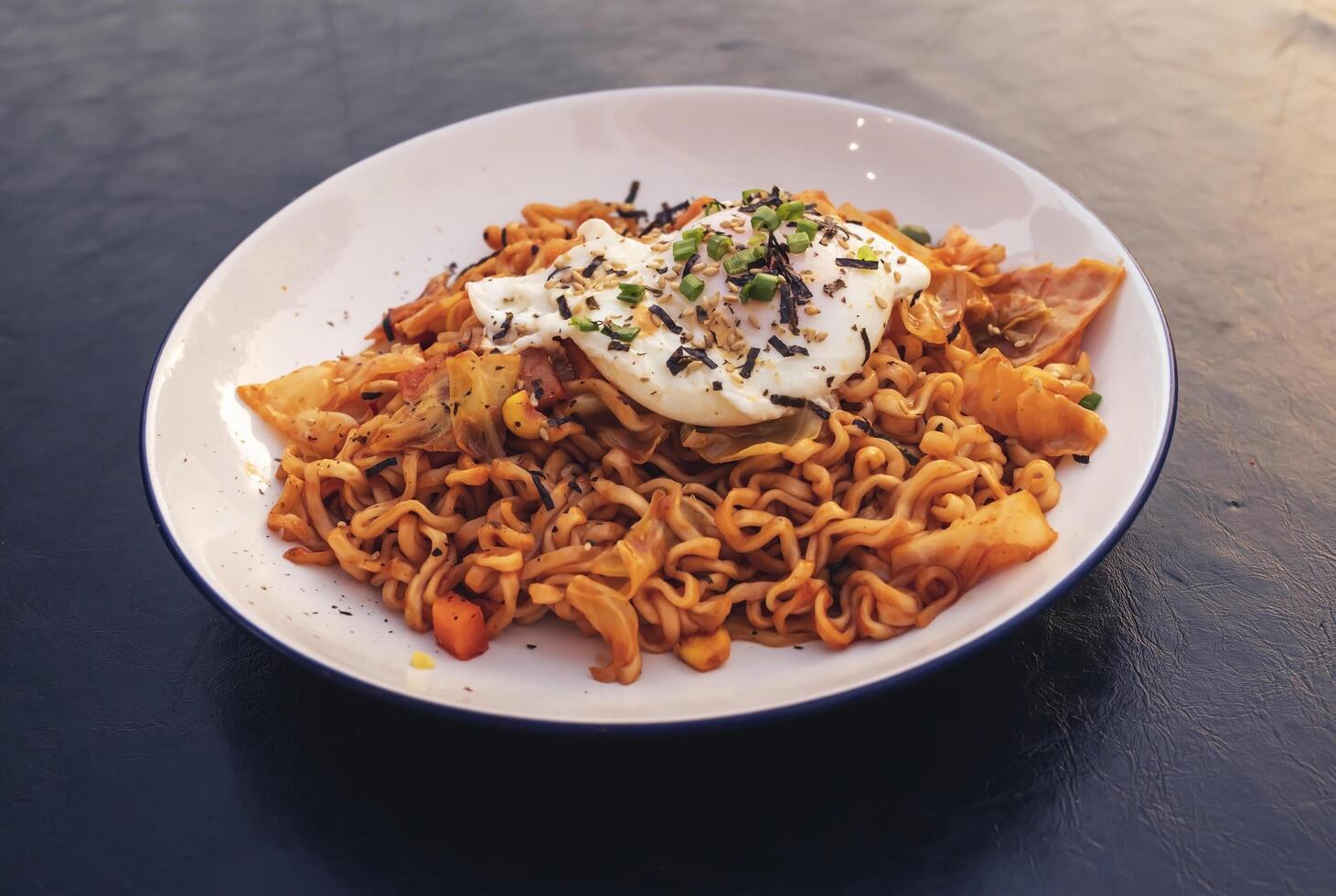 Stir fried noodles with fried egg topped with white sesame seeds and seaweed photo