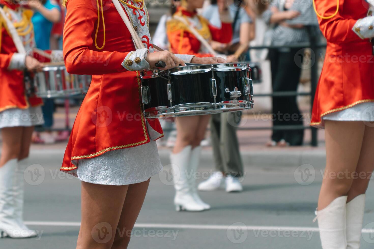 Young girls drummer in red vintage uniform at the parade. Street performance of festive march of drummers girls in red costumes on city street photo