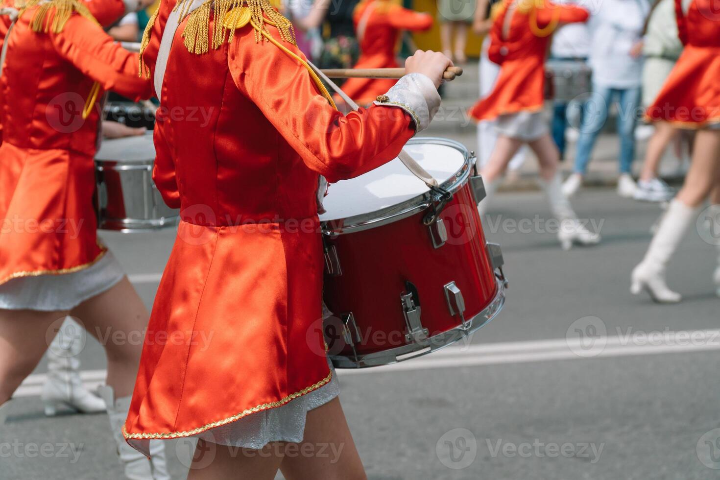 Young girls drummer in red vintage uniform at the parade. Street performance of festive march of drummers girls in red costumes on city street photo