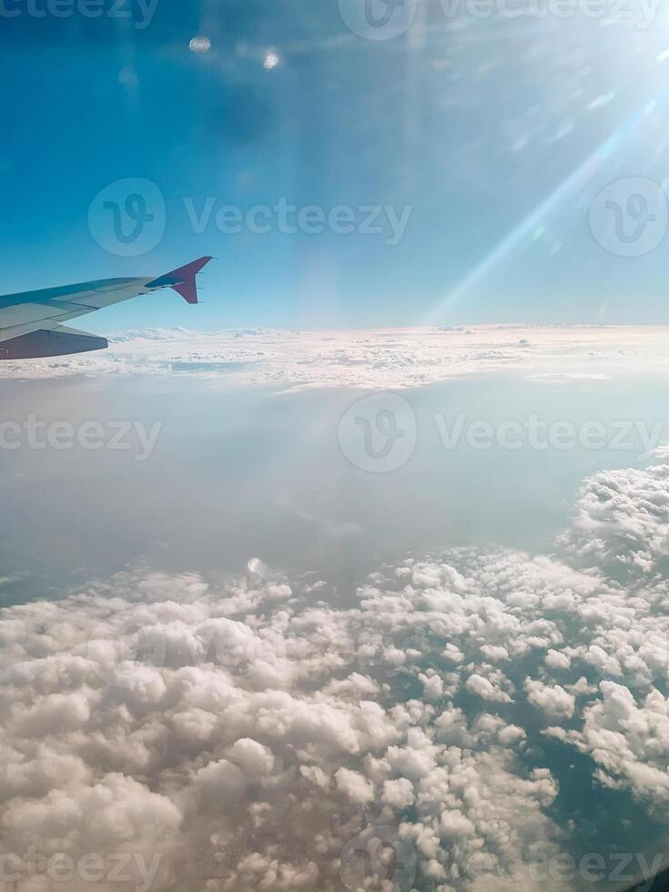 Cloudscape against blue sky through air plane window. Airplane in air with blue clouds. Airplane window photo