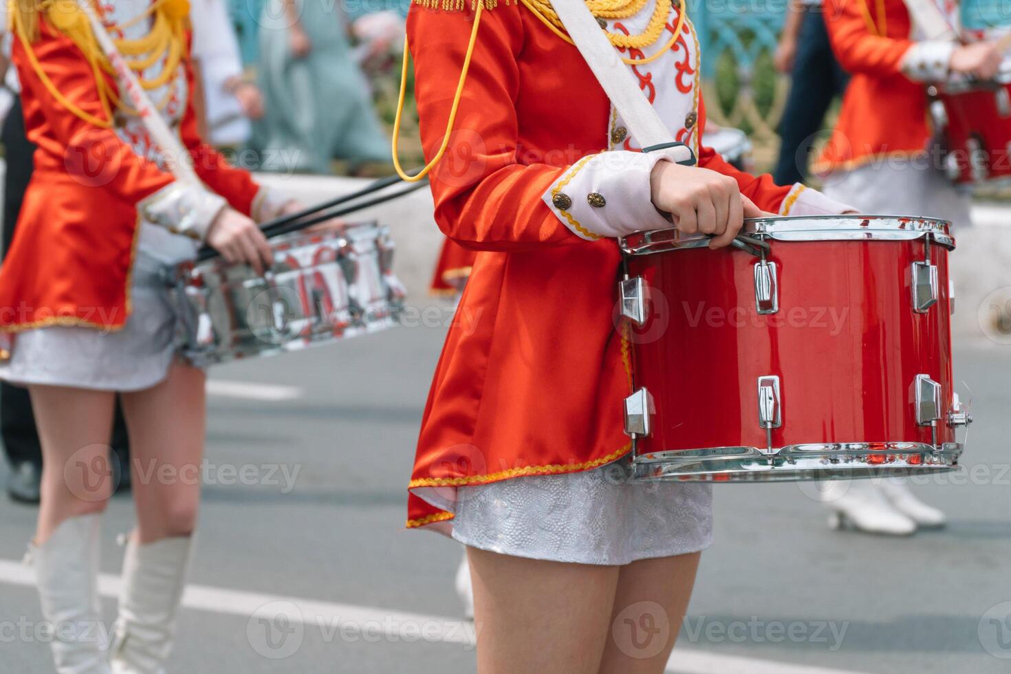 Street performance of festive march of drummers girls in red costumes on city street. Young girls drummer in red vintage uniform at the parade photo