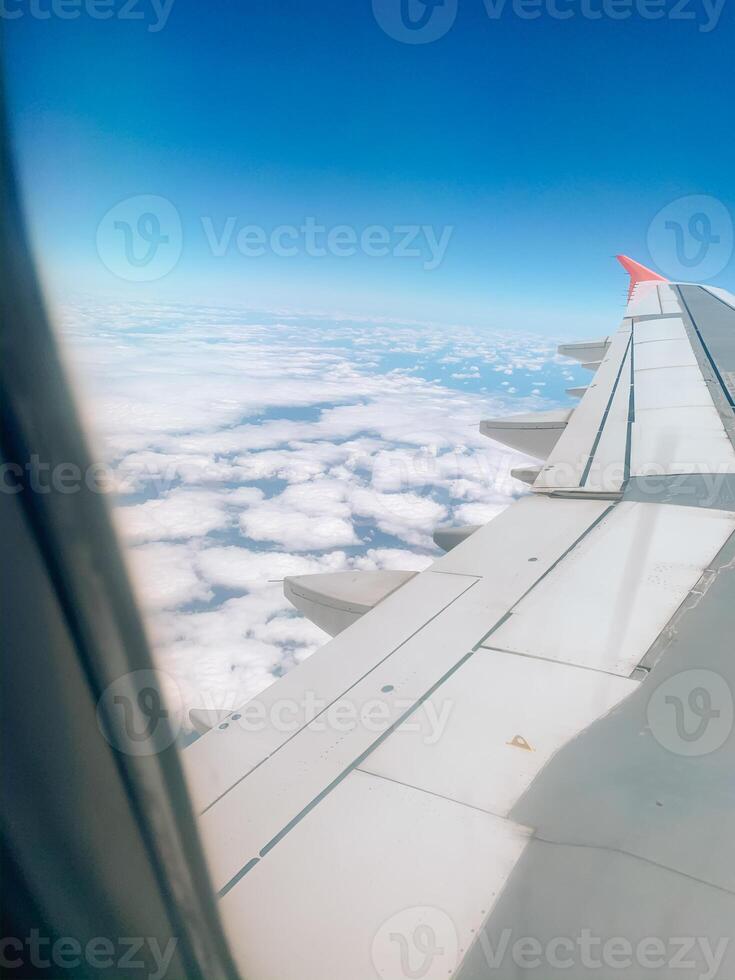 Airplane window. Traveling. Cloudscape against blue sky through air plane window photo