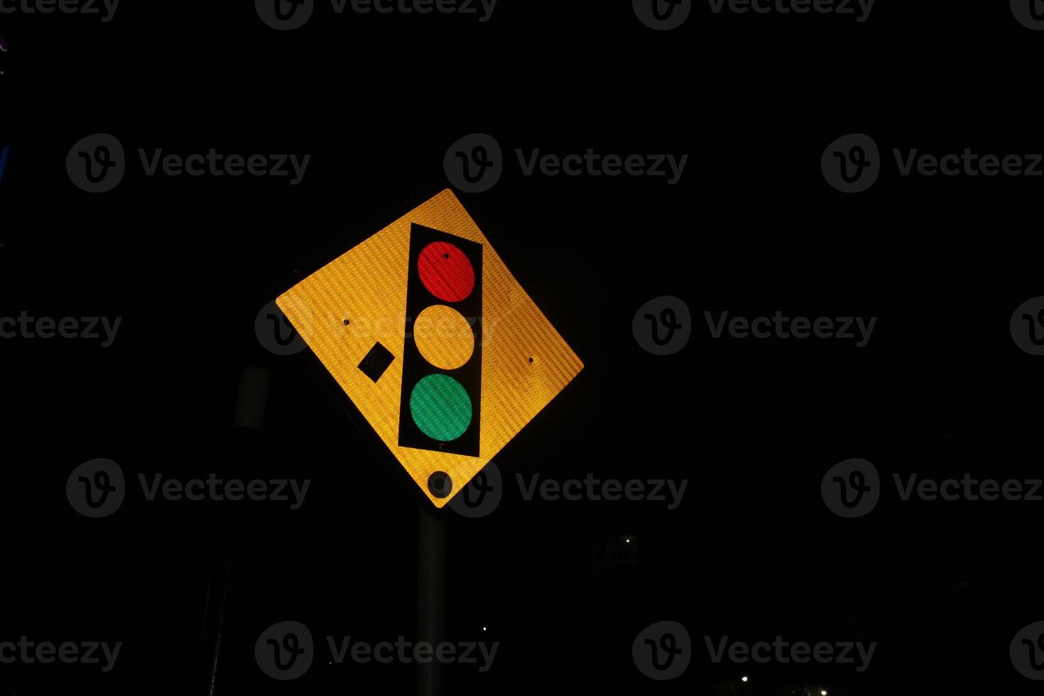 Photo of iron triangular traffic light signs at night