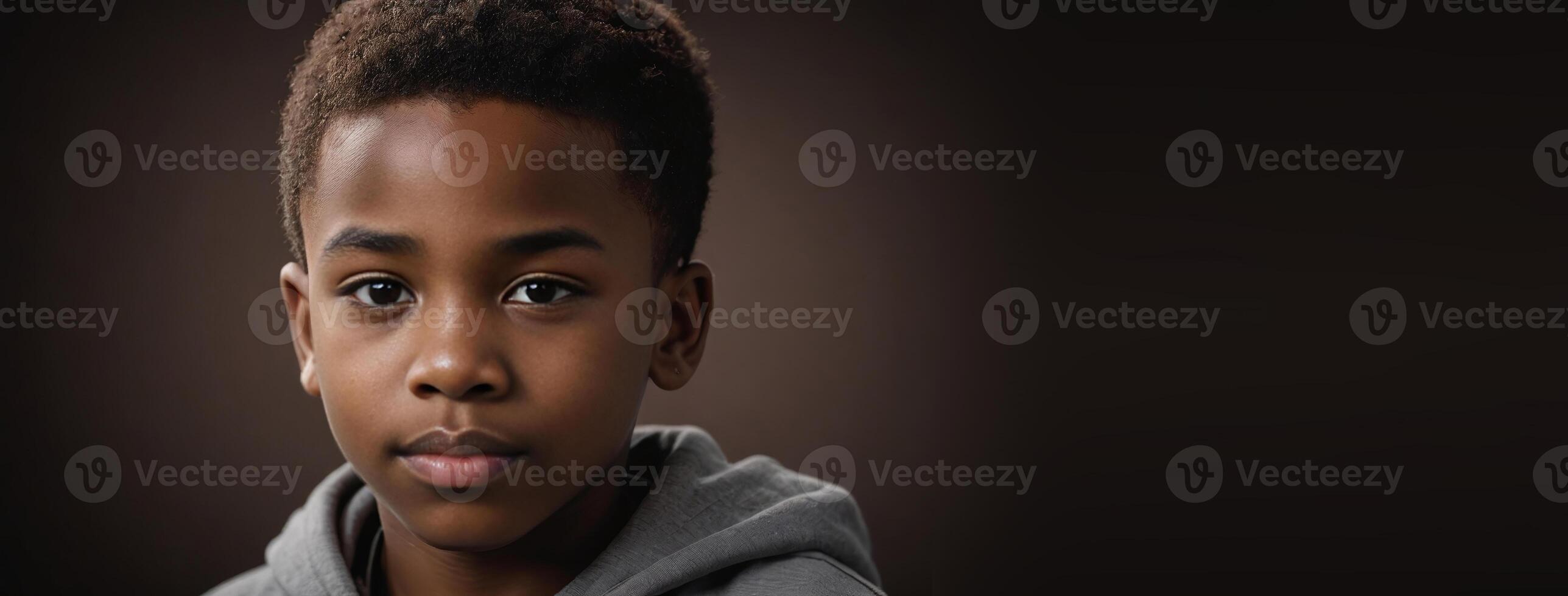 An African American Youngster Boy Isolated On A Dark Brown Background With Copy Space. photo