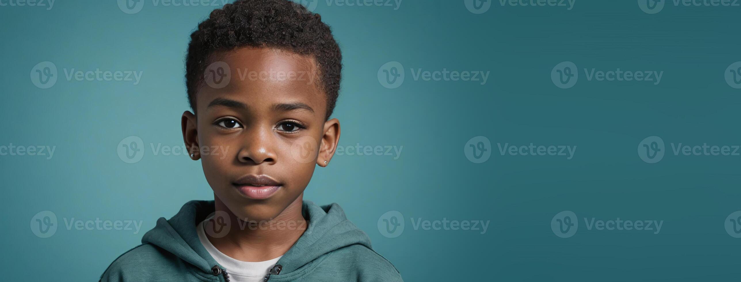 An African American Juvenile Boy Isolated On A Teal Background With Copy Space. photo