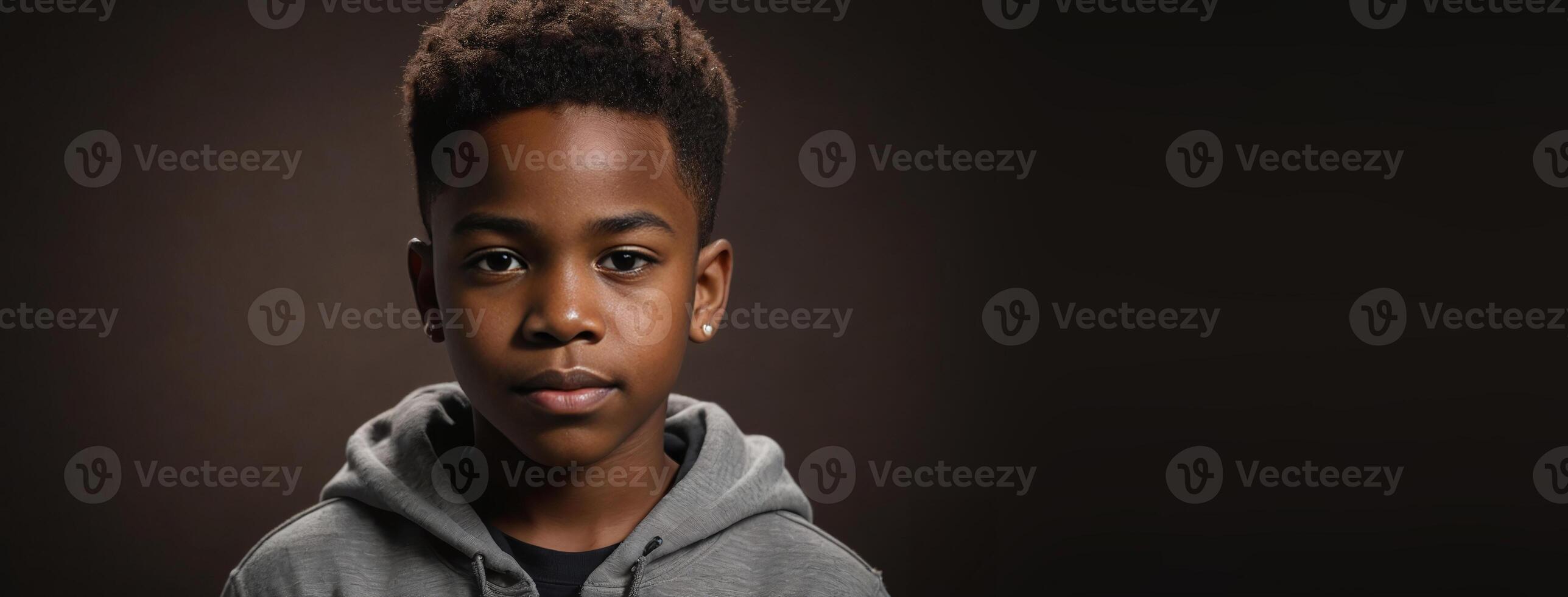 An African American Juvenile Boy Isolated On A Dark Brown Background With Copy Space. photo