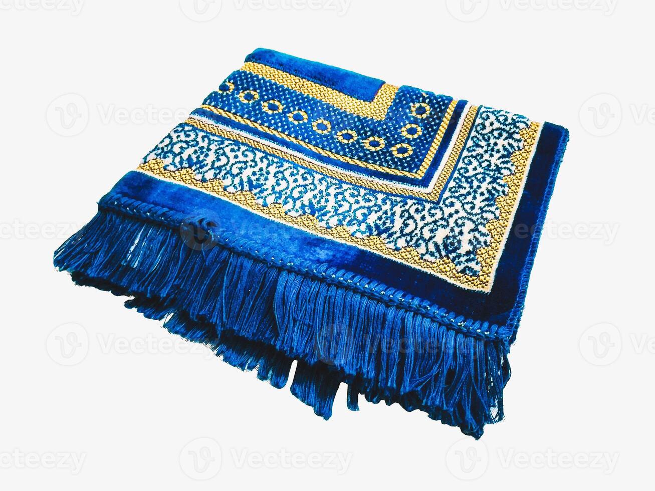 Folded Muslim prayer mat used to pay on white background photo