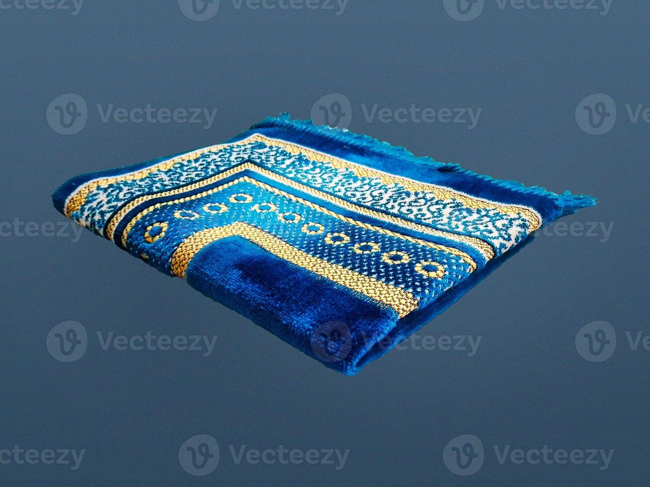 Folded Muslim prayer mat used to pay on dark background photo