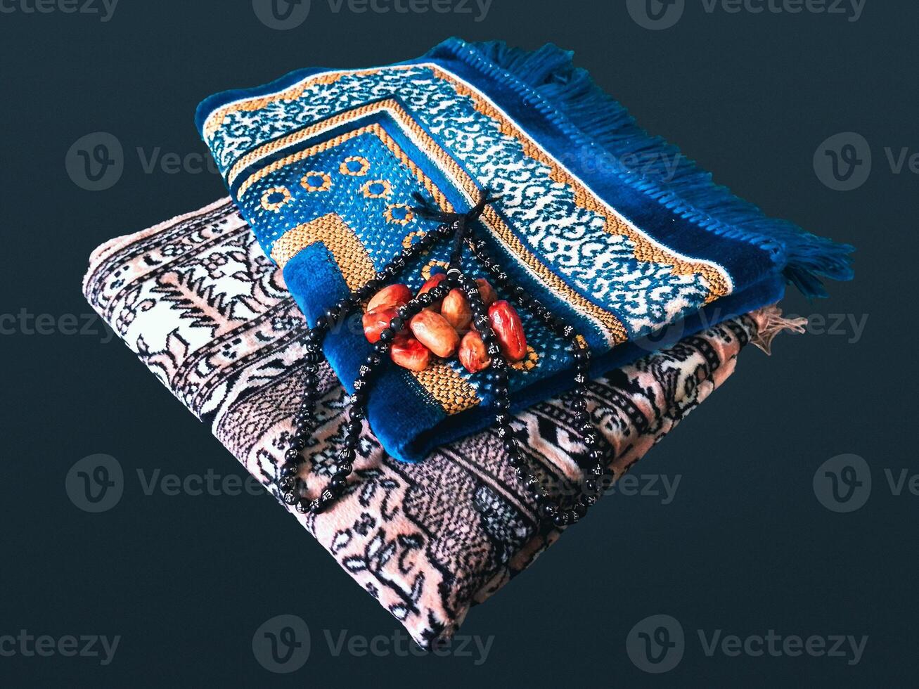 Folded Muslim prayer mat used to pay with tasbih and khajoor on black background photo