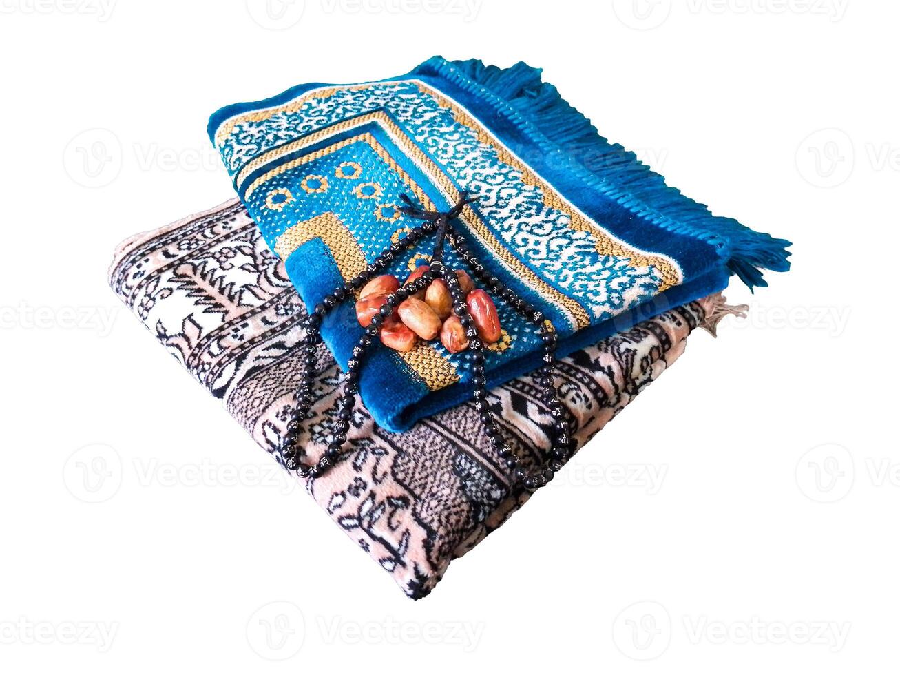 Folded Muslim prayer mat used to pay with tasbih and khajoor on white background photo