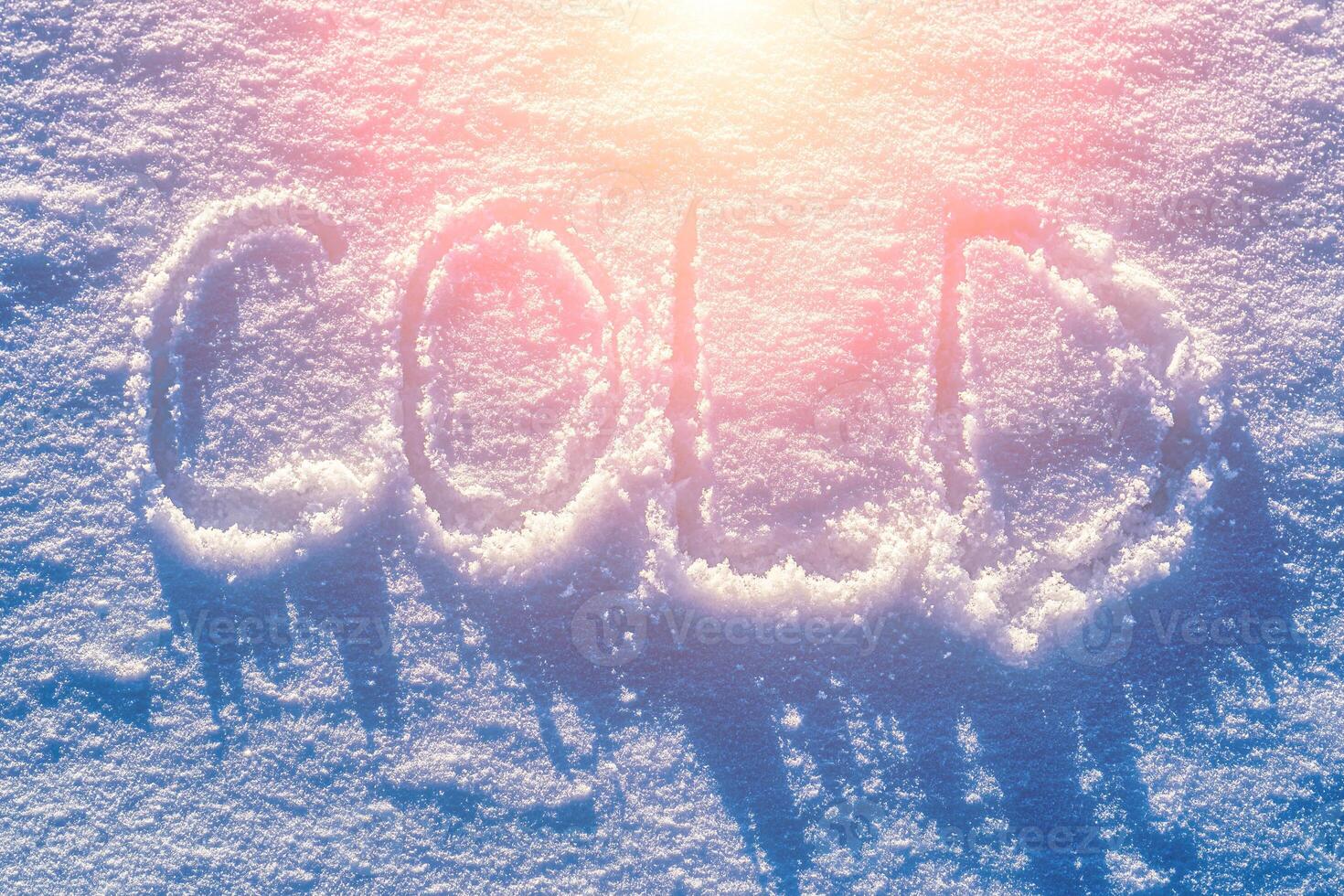 The word cold written on the snow. Winter and cold weather concept. photo