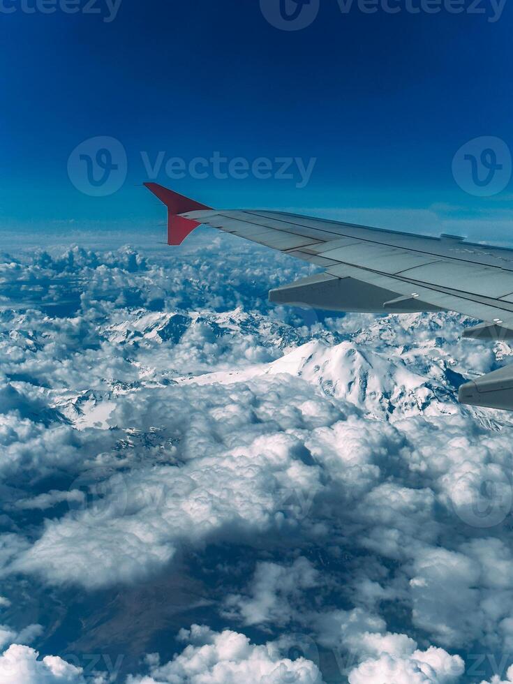 View of a steep rocky snow-capped mountain range from an airplane window photo