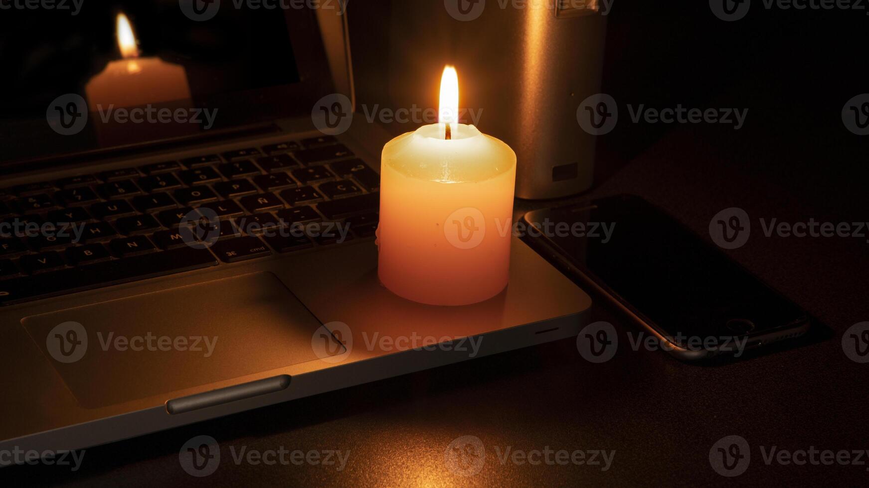 Blackout concept, A lit white candle on a laptop photo