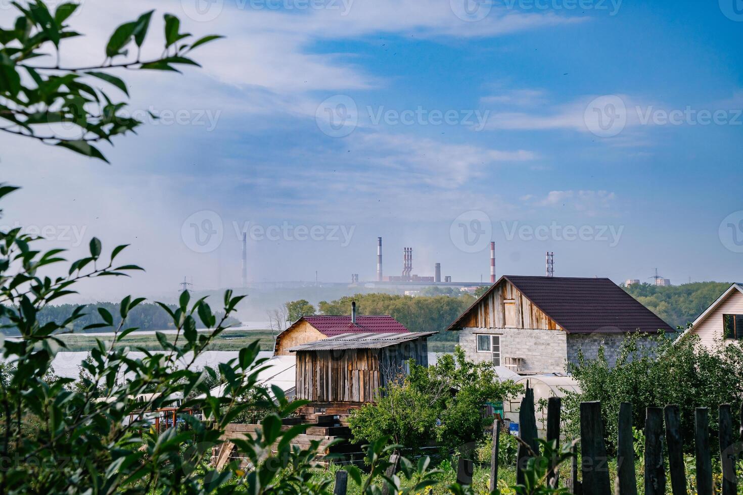 Green Village Near Factory with Tall Emitting Chimneys on a Summer Day photo