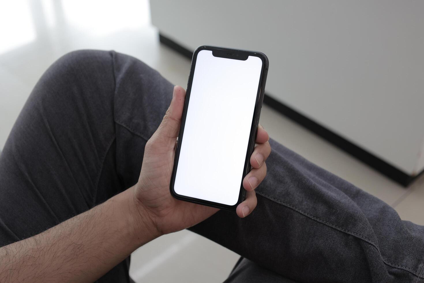 Hand holding smartphone in office, using phone photo