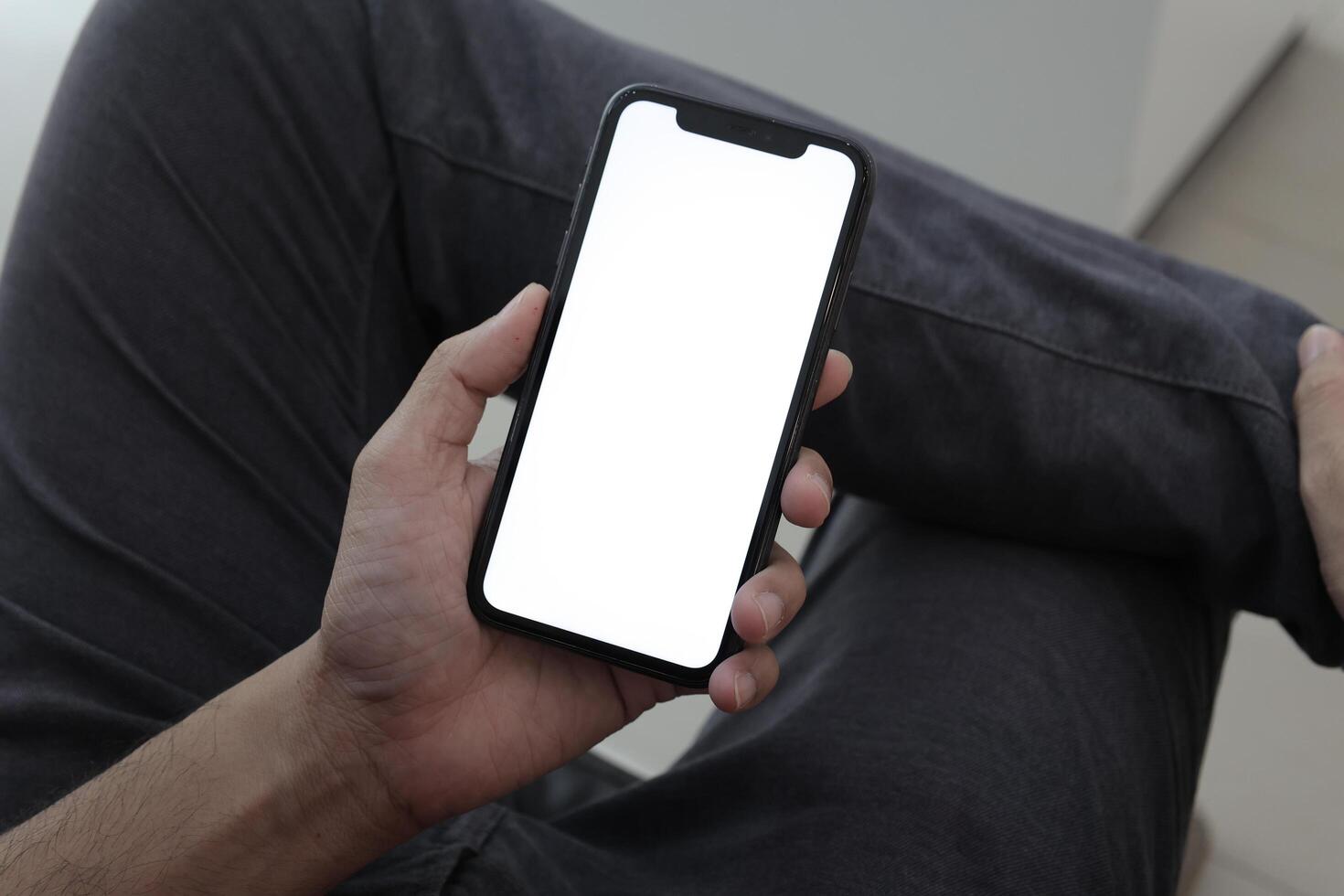 Hand holding smartphone in office, using phone photo
