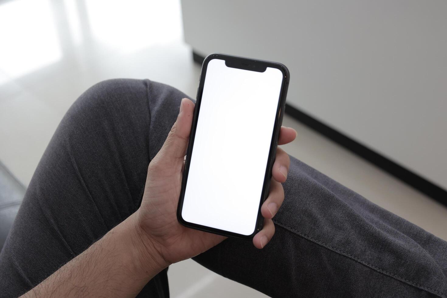 Hand holding smartphone in office, using phone photo