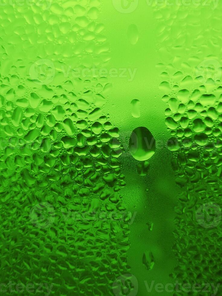 Water drops on glass, natural green background photo