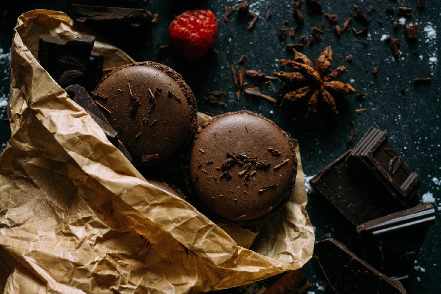 chocolate macarons with raspberry and chocolate on a dark background photo