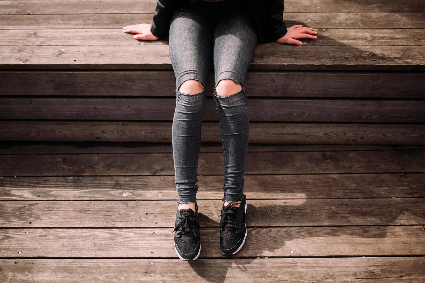 a person sitting on a bench with their legs crossed photo