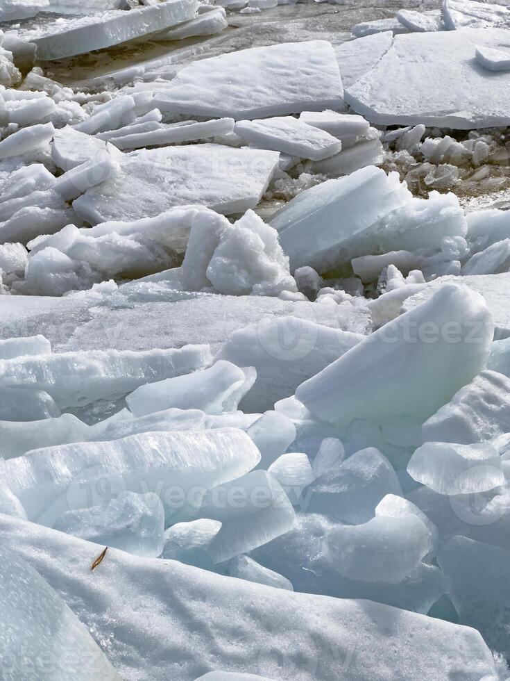 Close-up view of melting ice and snow revealing water and rocks beneath, a sign of seasonal change. photo