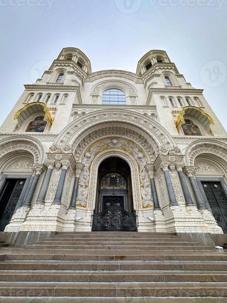 A stunning low-angle view of an Orthodox cathedral's entrance, adorned with intricate mosaics and golden domes, under a clear sky. photo